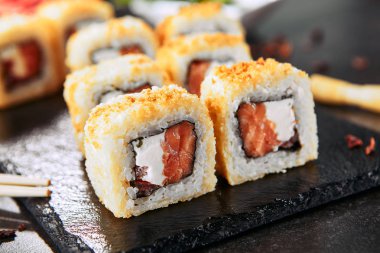 Krem peynir, çiğ somon, domates ve nori yosun ile sıcak gevrek tempura maki suşi rulo Makro atış. Doğal siyah taş kayrak arka plan closeup üzerinde derin kızarmış uramaki rulo seti