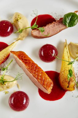 Zarif ördek meme, pişmiş armut ve kiraz küreler üst görünüm yaratıcı moleküler yemek servis. Doğal siyah mermer arka planda ızgara kümes hayvanları fileti ile Chef İtalyan çanak