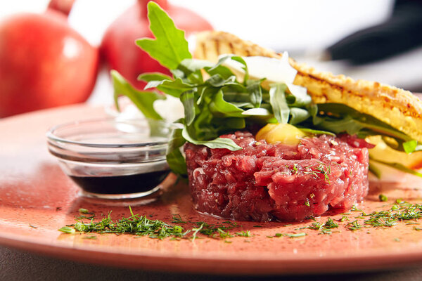 Steak Tartare Made from Raw Ground Beef with Greens Close Up