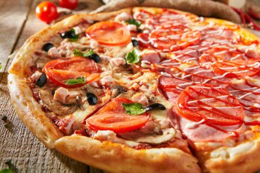 Pizza yarım tavuk ve mantar ve Yeşiller, diğer yandan - jambon ve sos ile. Rustik ahşap arka plan üzerinde taze sebze ile