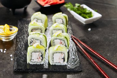 Krem peynir, kar yengeç, salatalık, uçan balık havyar, mayonez, limon ve nori closeup ile Uramaki suşi rulo. Koyu bulanık arka plan üzerinde deniz ürünleri suşi Makro çekim