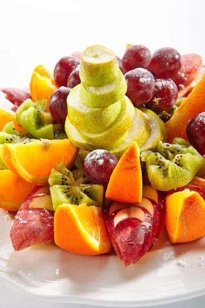 Ovocná deska s oranžovými klíny, jablky, hrozny, kiwi a hrušeň — Stock fotografie