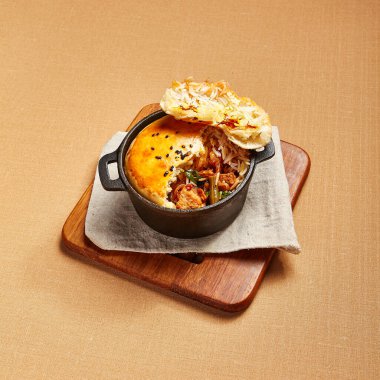 Hamurlu tavuk çorbası. Kümes hayvanları, dökme demir tabakta pirinçle pişiriliyor. Restoran yemeği, yukarıdan servis ediliyor. Güzel yemek bölümü. Et ve sebze dolgulu ekmek. Aşçılık sanatı