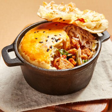 Hamurlu tavuk çorbası. Kümes hayvanları, dökme demir tabakta pirinçle pişiriliyor. Restoran yemeği, yukarıdan servis ediliyor. Güzel yemek bölümü. Et ve sebze dolgulu ekmek. Aşçılık sanatı