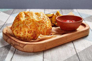 Kızarmış yuvarlak peynirli ekmek ve kızarmış patates. Restoran yemeği porsiyonu. Ahşap tepside domates soslu fast food servisi. Cafe fast food yakın çekim. Rota yan çekimi