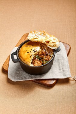 Hamurlu tavuk çorbası. Kümes hayvanları, dökme demir tabakta pirinçle pişiriliyor. Restoran yemeği, yukarıdan servis ediliyor. Güzel yemek bölümü. Et ve sebze dolgulu ekmek. Aşçılık sanatı