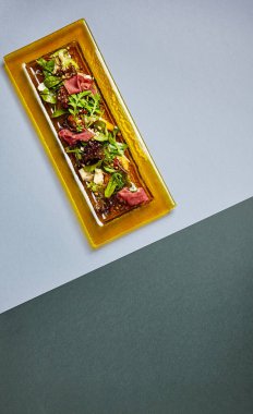 Marul ve jamonlu salata. Şeffaf sarı tabakta servis edilen süslü et ve sebzeler. Koyu masa manzaralı lüks garnitür. Lezzetli bir restoran kursu.