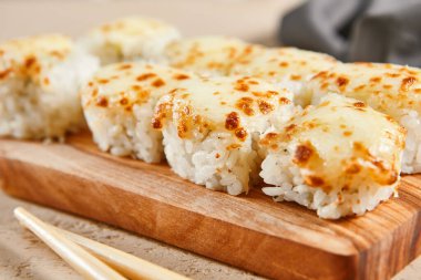 Ahşap tahta manzaralı fırınlanmış karides ruloları. Lezzetli sıcak suşi, soya soslu somon filetosu ve sashimi. Asya yemekleri, geleneksel Japon yemekleri, çubuklu deniz ürünleri.