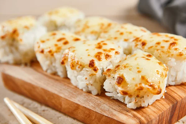 Ahşap tahta manzaralı fırınlanmış karides ruloları. Lezzetli sıcak suşi, soya soslu somon filetosu ve sashimi. Asya yemekleri, geleneksel Japon yemekleri, çubuklu deniz ürünleri.