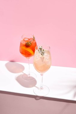 Pembe arka planda Aperol Spritz Kokteyli. Güneş ışığı ve gölge arkaplan. Pembe ve beyaz minimal