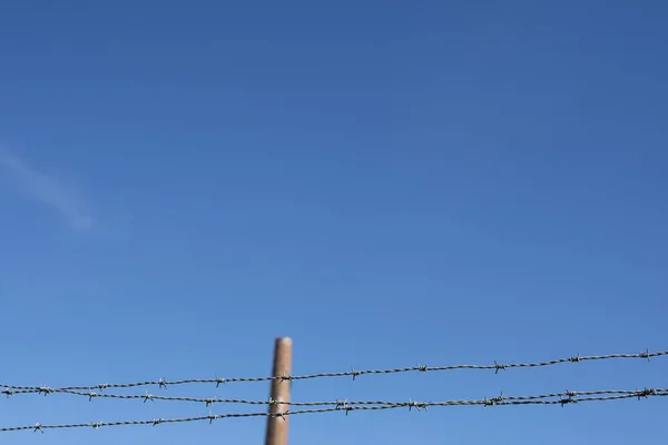 Closup Van Prikkeldraad Met Industriële Schoorsteen Achtergrond Tegen Blauwe Hemel — Stockfoto