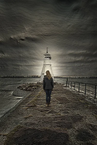 Sanatsal crative güçlü bir deniz feneri ile bir iskelede duran tanınmaz halde genç kadının dramatik bir etki için görüntü dokulu.