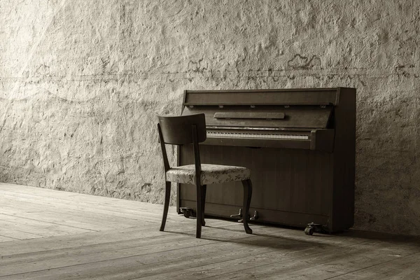 Oude piano in oude kamer met stenen muren en houten vloer — Stockfoto