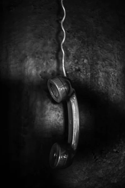 Analog telephone reseiver hanging from cord in black and white — Stock Photo, Image