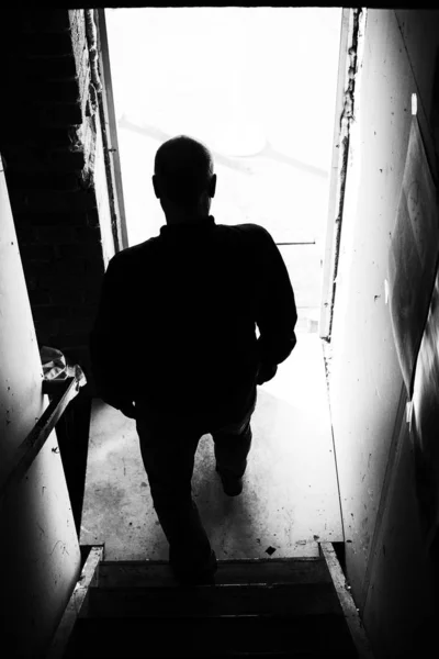 Silhouette of unrecognizable man walking down the stairs toward — Stock Photo, Image