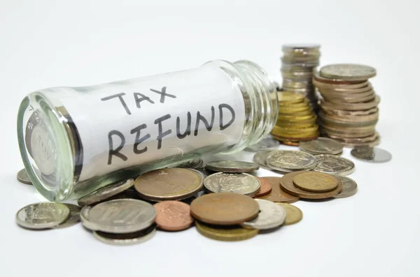 白い背景にコインがこぼれるガラス瓶内の税金還付表 — ストック写真