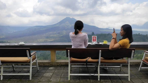 Jovens mulheres apreciam o café com fundo do Monte Batur volc — Fotografia de Stock