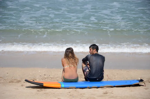 Pareja joven relajarse, tomar el sol, sentarse en la arena blanca, ver en el mar — Foto de Stock