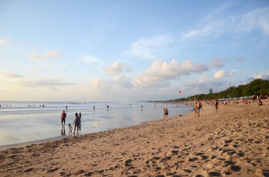 İnsanlar Kuta, Bali sahilinde dramatik günbatımının tadını çıkarıyorlar.