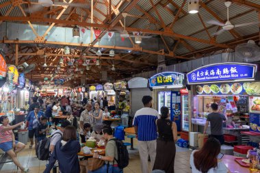 Singapur - 30 Ağustos 2025: Kalabalık kalabalık Singapur 'daki Maxwell Hawker Center' ı ziyaret ederek çeşitli yerel yiyecek tezgahlarıyla dolu canlı bir atmosferin keyfini çıkarıyor..