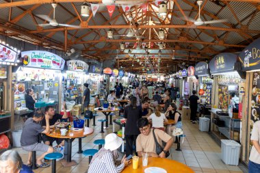Singapur - 30 Ağustos 2025: Kalabalık kalabalık Singapur 'daki Maxwell Hawker Center' ı ziyaret ederek çeşitli yerel yiyecek tezgahlarıyla dolu canlı bir atmosferin keyfini çıkarıyor..