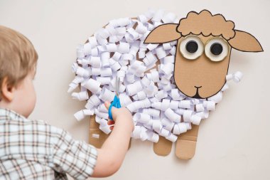 Çocuk bir kağıt koyun kesti. Oyuncak bebek. Evde faaliyet var. Erken eğitim, iyi motor beceriler. Montessori yöntembilimi.