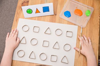 Çocuk geometrik şekilleri öğreniyor. Güzel motor beceriler. Anaokulu ya da özel görevler. Çocukların erken eğitimi. Montessori yöntembilimi.