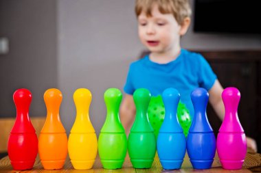 Çocuklar bir çocuk topu evin bovling salonuna attı ve lobutları kırdı. Seçici odaklanma. Ana odada aktif oyun konsepti, karantina, kendini izole etme, hedefe ulaşmak.