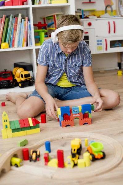 Menino Com Fones Ouvido Joga Chão Com Brinquedos Madeira Carris — Fotografia de Stock