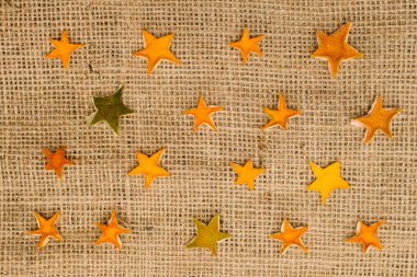 Kurutulmuş portakal kabuğundan yapılmış turuncu yıldızlar keten kumaş üzerinde. Noel süsü. Advent süslemeleri.
