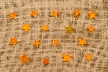 Kurutulmuş portakal kabuğundan yapılmış turuncu yıldızlar keten kumaş üzerinde. Noel süsü. Advent süslemeleri.