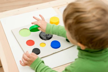 Bir eşleşme bul. Çocuk farklı boyut ve renkte plastik başlıkları eşleşen deliklere sokuyor. Dolayısıyla eğitim ve beyin egzersizi için terapi görevi. DIY oyun oynuyor. çocuklar ve engelliler için iyi motor becerileri