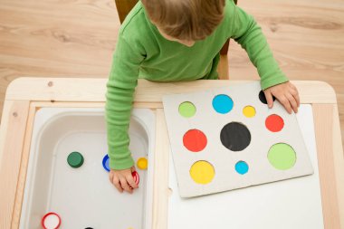 Bir eşleşme bul. Çocuk farklı boyut ve renkte plastik başlıkları eşleşen deliklere sokuyor. Dolayısıyla eğitim ve beyin egzersizi için terapi görevi. DIY oyun oynuyor. çocuklar ve engelliler için iyi motor becerileri