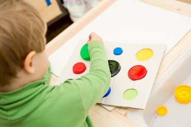 Bir eşleşme bul. Çocuk farklı boyut ve renkte plastik başlıkları eşleşen deliklere sokuyor. Dolayısıyla eğitim ve beyin egzersizi için terapi görevi. DIY oyun oynuyor. çocuklar ve engelliler için iyi motor becerileri