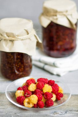 bir tabak ve bardak taze ahududu yemek, ev yapımı tatlılar ahşap bir masa, hazırlıklar, ev yapımı ile ahududu reçeli kavanozlar