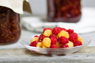 bir tabak ve bardak taze ahududu yemek, ev yapımı tatlılar ahşap bir masa, hazırlıklar, ev yapımı ile ahududu reçeli kavanozlar