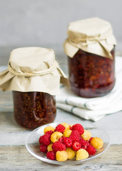 bir tabak ve bardak taze ahududu yemek, ev yapımı tatlılar ahşap bir masa, hazırlıklar, ev yapımı ile ahududu reçeli kavanozlar