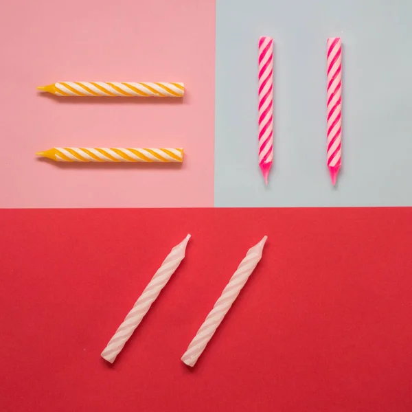 Multi-colored striped candles for birthday on the pastel colored background. Minimalism. Flat lay.