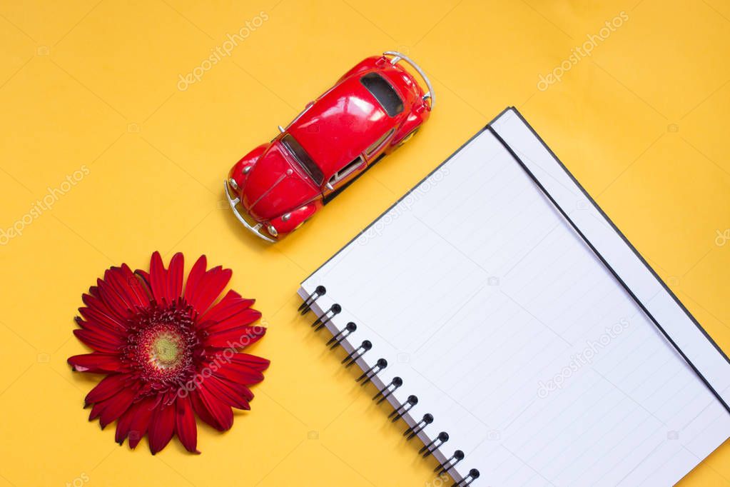 minimalist Flat lay, yellow, red colors, gerbera, toy car, notebook