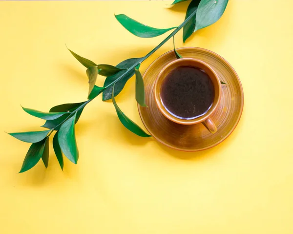 シンプルなフラットを産むが 黄色の背景で一杯のコーヒー 緑の枝 — ストック写真