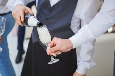 Garson şampanya bir şişe kadehlerin içine düğün Konuklar için dökülen.