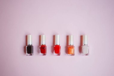 çok renkli tırnak cilaları üstten görünüm, pastel pembe arka plan üzerinde düz yatıyordu. Birçok kavanoz ile çok renkli oje için yuvarlak.