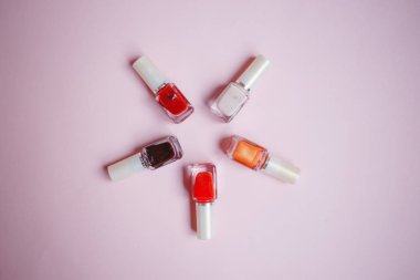 çok renkli tırnak cilaları üstten görünüm, pastel pembe arka plan üzerinde düz yatıyordu. Birçok kavanoz ile çok renkli oje için yuvarlak.