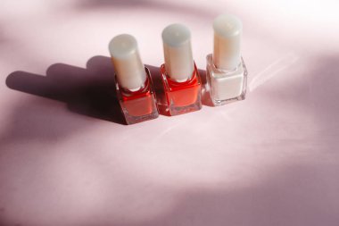 çok renkli tırnak cilaları üstten görünüm, pastel pembe arka plan üzerinde düz yatıyordu. Birçok kavanoz ile çok renkli oje için yuvarlak.