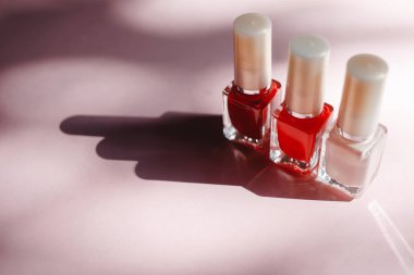 çok renkli tırnak cilaları üstten görünüm, pastel pembe arka plan üzerinde düz yatıyordu. Birçok kavanoz ile çok renkli oje için yuvarlak.