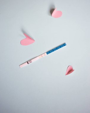 İki şeritler ve pembe kalpler ile pozitif gebelik testi. mavi arka plan, kopya alanı
