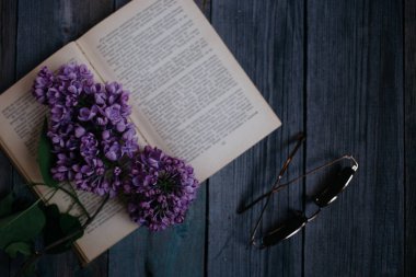 Lila açık kitap üzerine, ahşap bir masa üzerinde güneş gözlüğü Şubesi