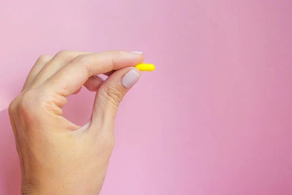 Vrouw Hand Met Gele Pil Capsule Roze Achtergrond Medicatie Concept — Stockfoto