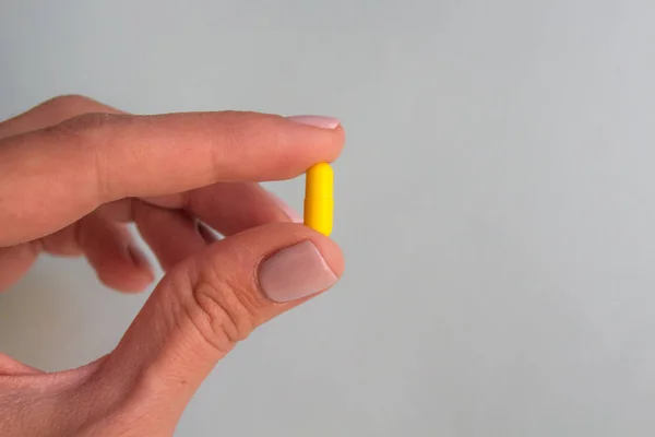 Mujer Mano Sosteniendo Cápsula Píldora Amarilla Sobre Fondo Azul Claro —  Fotos de Stock