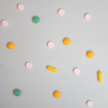 Beyaz, yeşil ve turuncu hap ve tabletler üzerinde mavi bir arka plan deseni. Çeşitli ilaç tıp hapları, düz yatıyordu